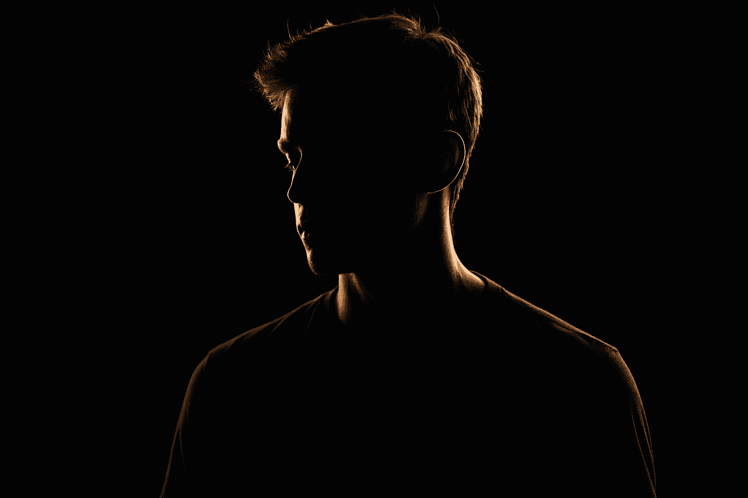 Portrait of a person with high contrast rim lighting highlighting sharp edges against a dark background